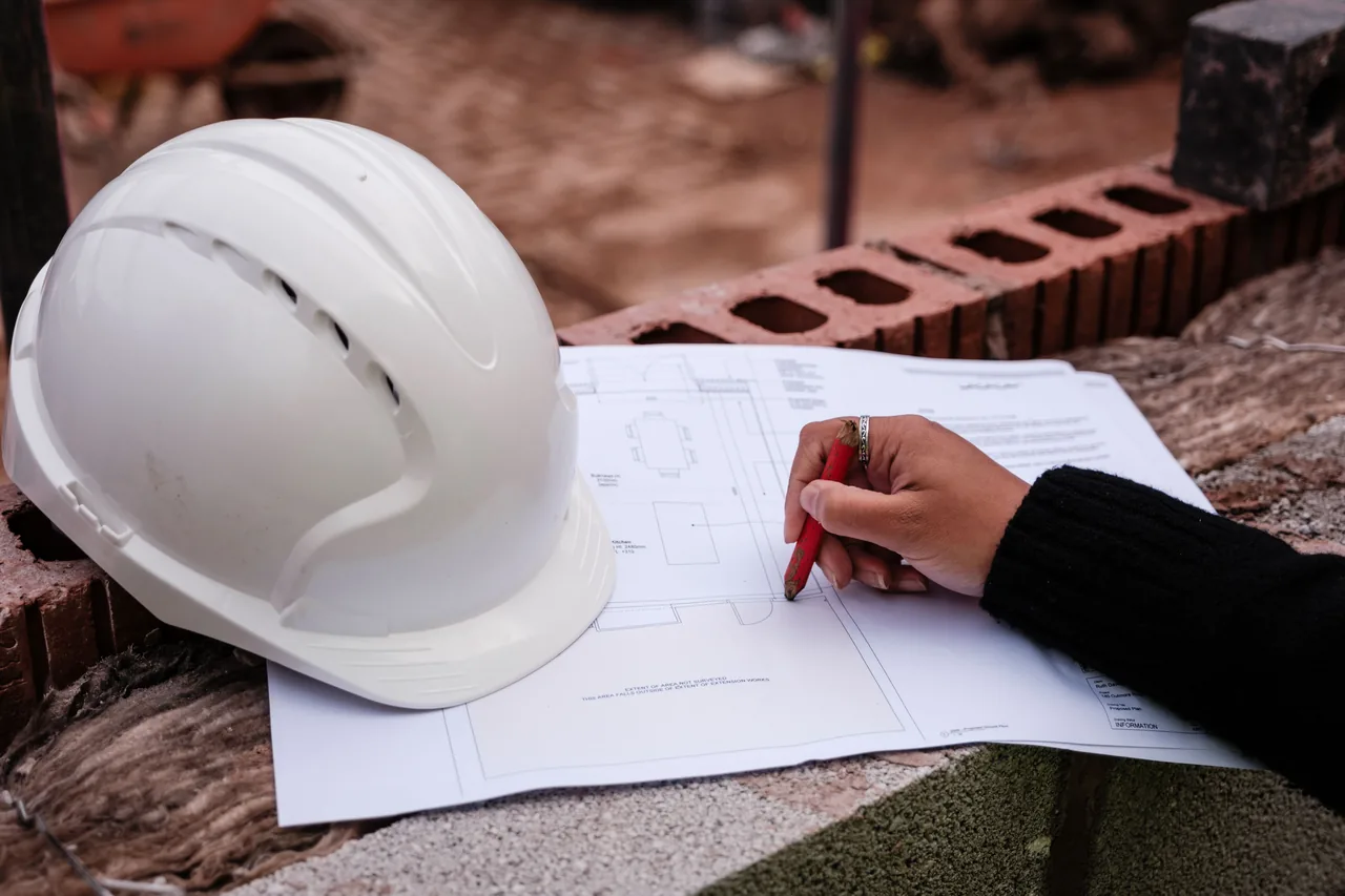 A hard hat resting on a marked-up services drawing at the specification stage of a project