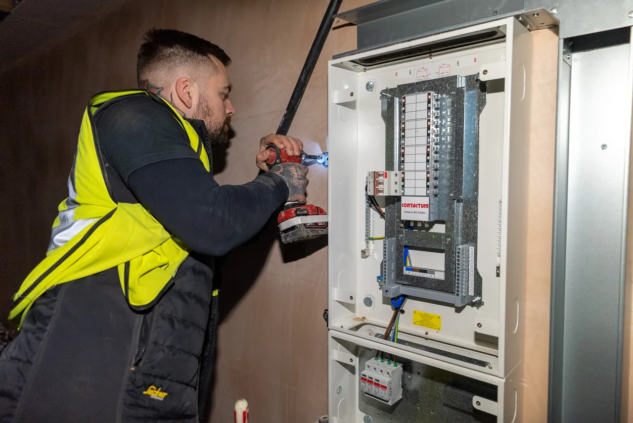 An electrician terminating circuits at a consumer unit while commissioning an installation