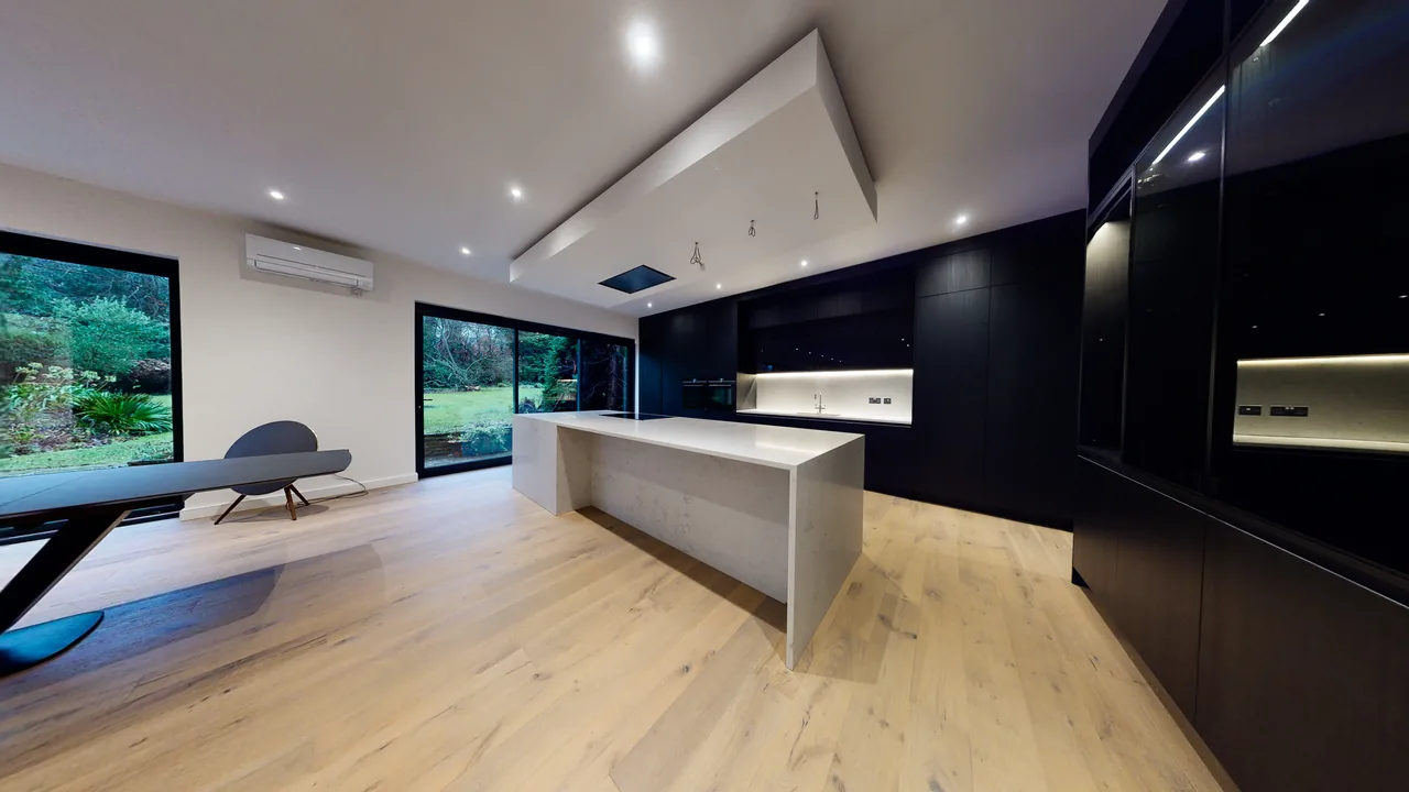 A wall-mounted air conditioning unit set discreetly above a dark kitchen island