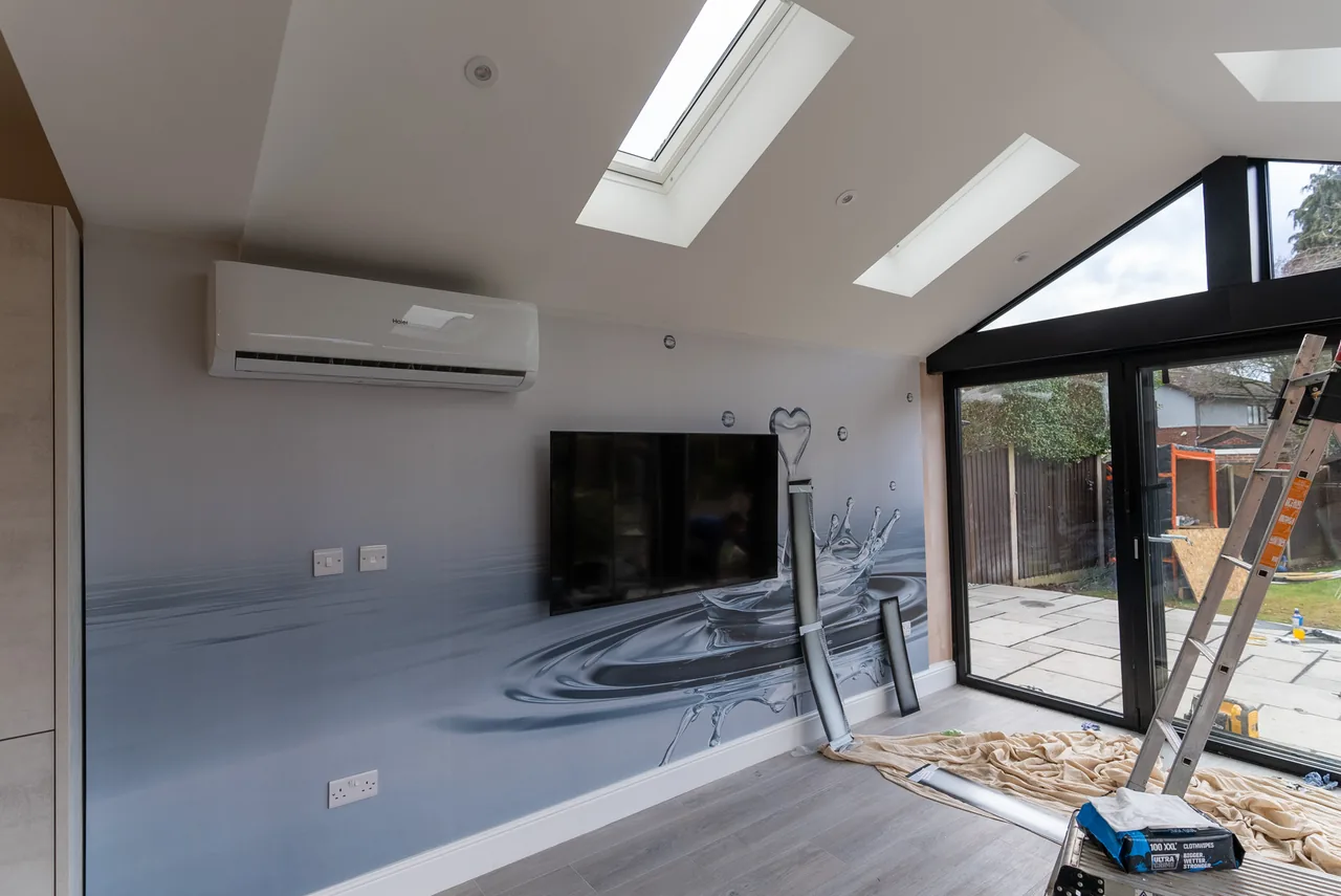 A wall-mounted air conditioning unit installed above a television in a finished room