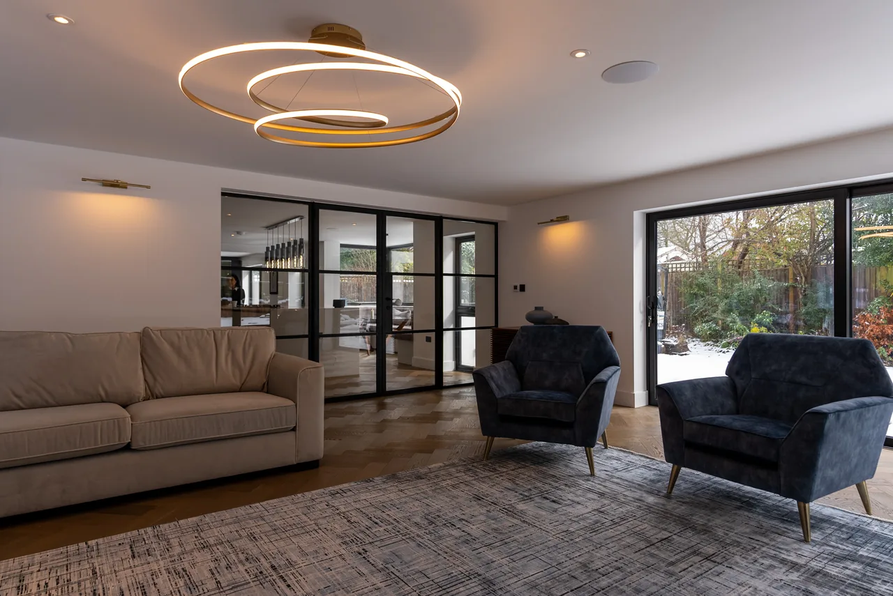An open-plan living room lit by a sculptural ring pendant with glazing onto the garden