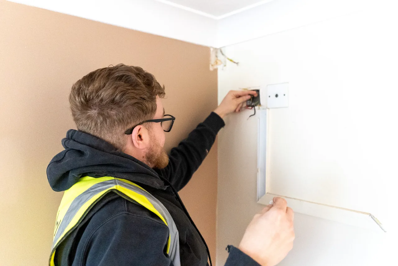 An engineer fitting a wall control plate in a finished room