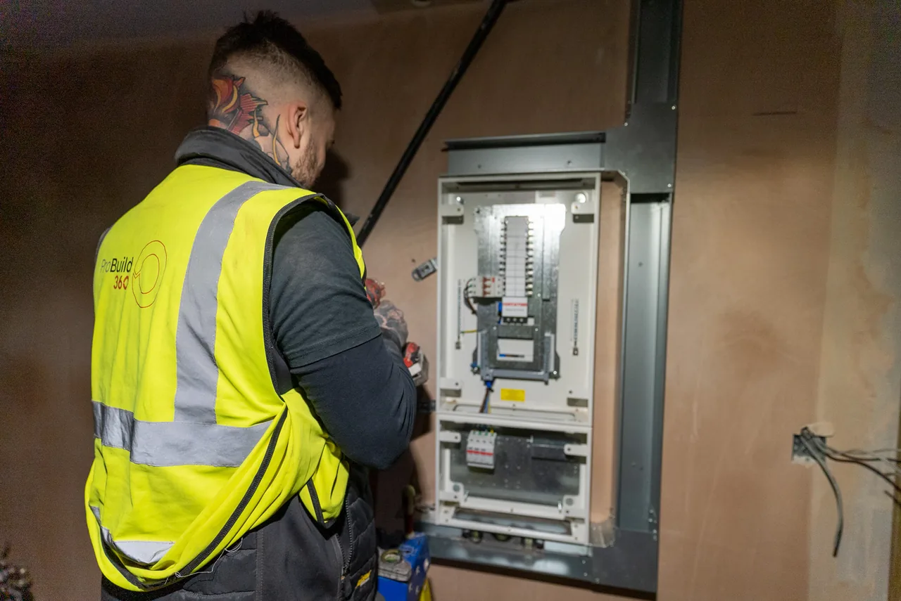 An electrician working at an open distribution board on a commercial installation