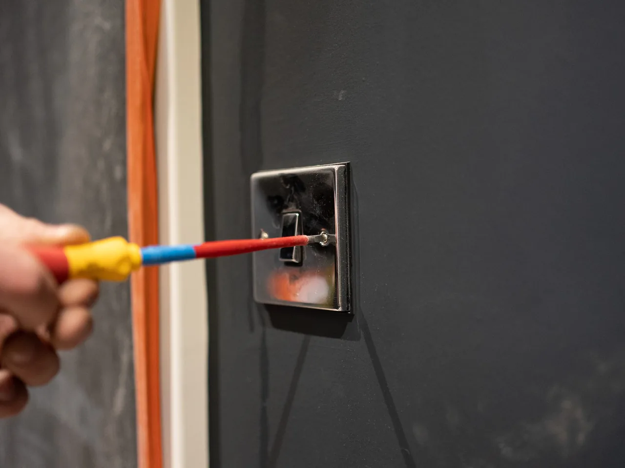 A finished socket outlet set into a dark painted wall