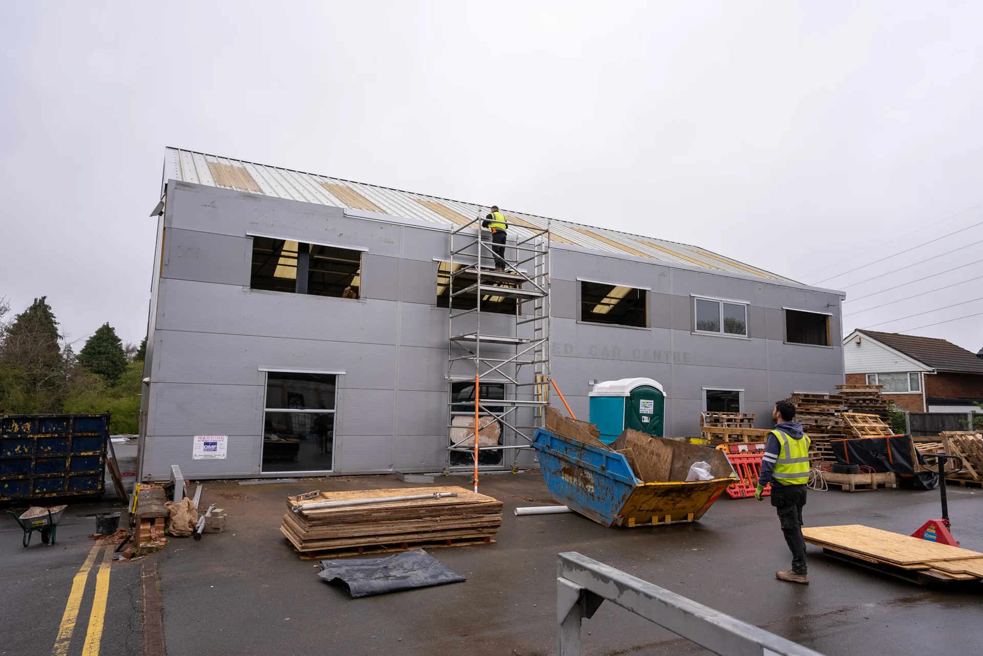 A commercial building under construction with scaffolding, site plant and materials on the deck